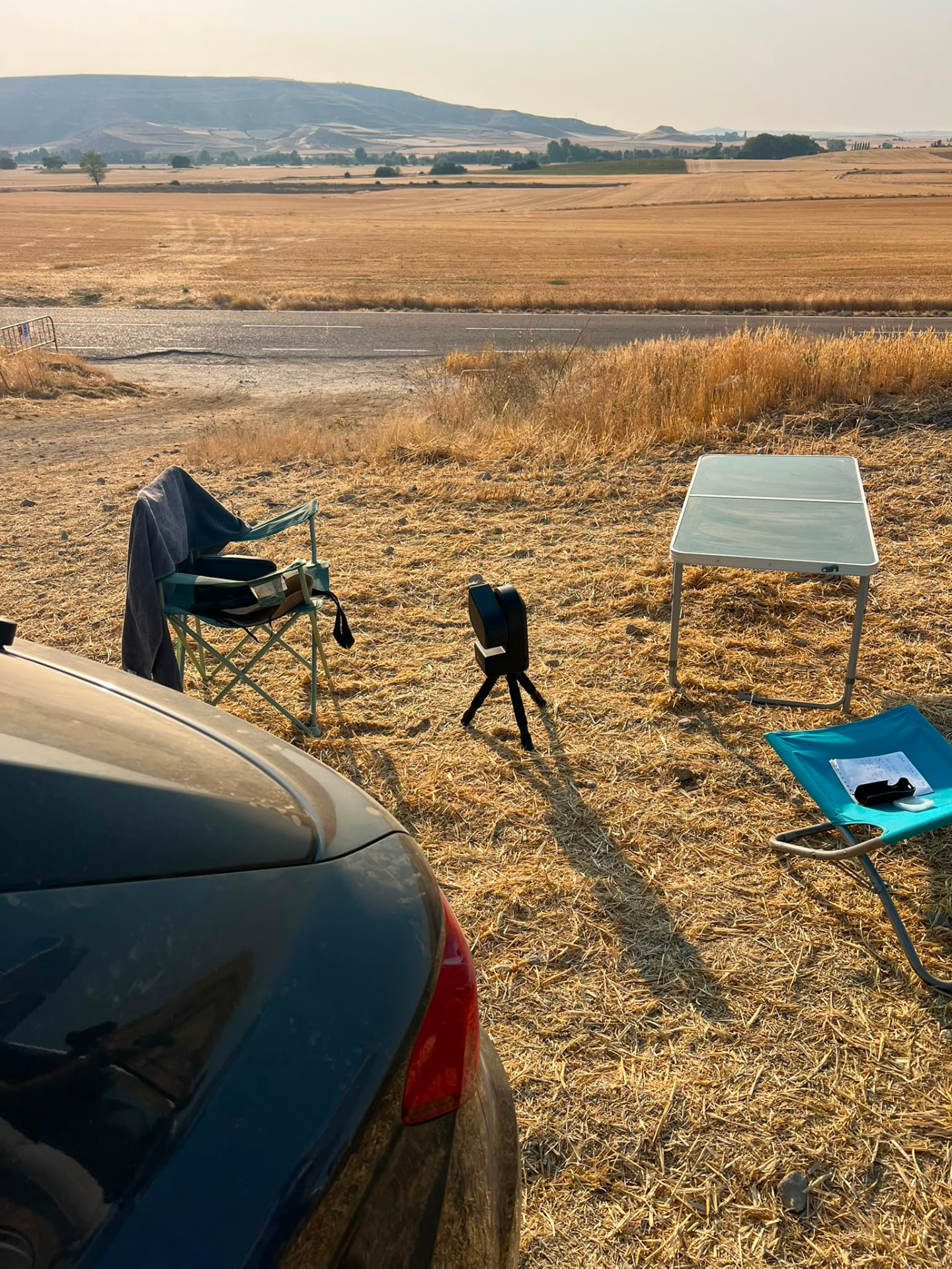 Le Seestar S50 sur son petit trépied à côté de la table et des fauteuils, face aux champs